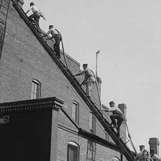 A team of Firefighters with Hoses on Their backs climbs a ladder