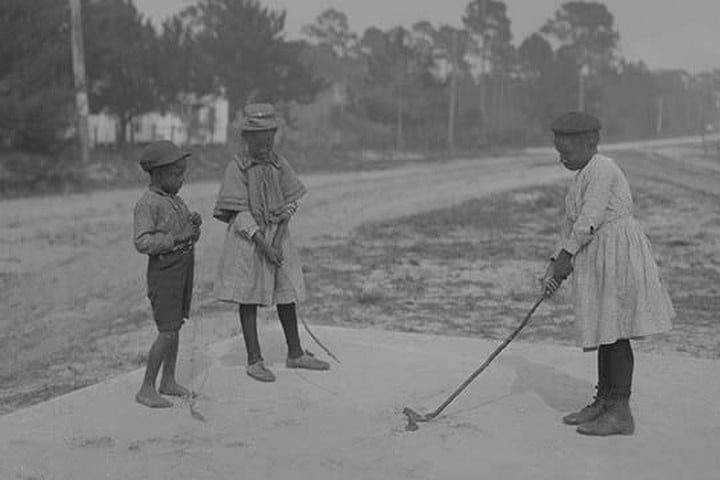 African American Children pretend to play golf on country road
