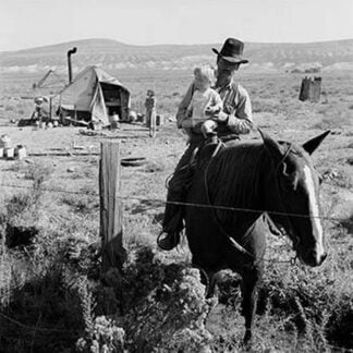 Cowboy holds his baby while riding a horse by Dorothea Lange
