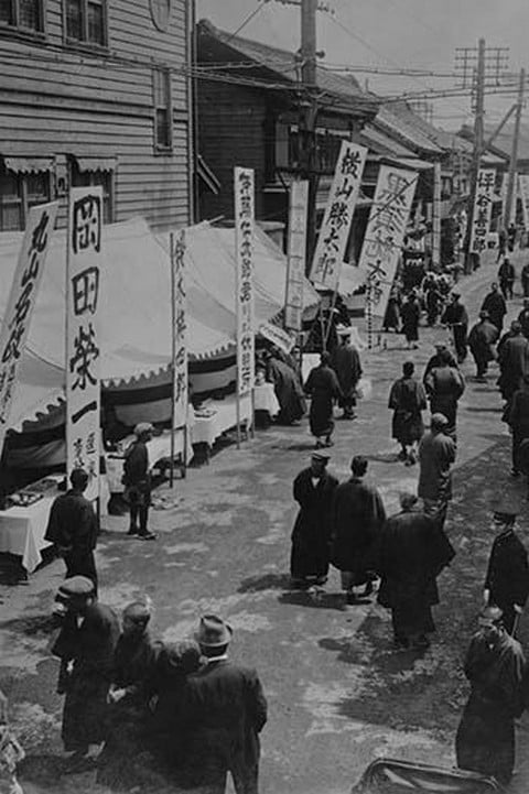 Election Day in Tokyo Japan shows a line of tables with signs in Kanji advertising political candidates