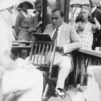 Enrico Caruso Leans back on chair holding a Board with Music