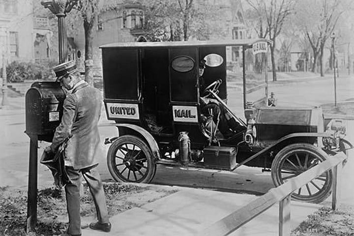 Mailman at Post Box with his truck parked at the curb