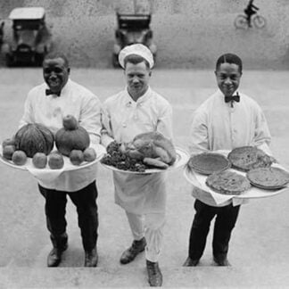 Three Chefs stand on bottom of a line of steps and hold up Thanksgiving platters of Pies