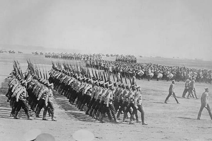 Tsarist Troops parade and pass in Review in Formation across field while a marching band plays