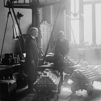 Two suited men weigh bars of gold on scales at the US Mint